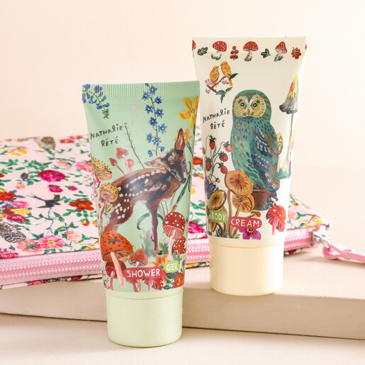 Heathcote & Ivory Nathalie Lété Forest Folk Travel Wash Bag with products outside of packaging against beige coloured backdrop