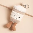 Jellycat Amuseable Coffee-To-Go Bag Charm laid on top of beige coloured backdrop