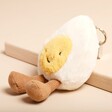 Jellycat Amuseable Happy Boiled Egg Bag Charm sitting on pink surface