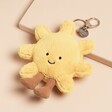 Jellycat Amuseable Sun Bag Charm laid on top of beige coloured backdrop