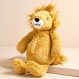 Jellycat Small Bashful Lion Soft Toy sat on top of raised beige surface