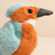 Close up of Jellycat Birdling Kingfisher Soft Toy against beige backdrop