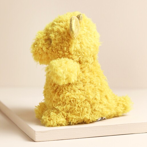 Side of Jellycat Little Dragon Soft Toy in front of beige backdrop