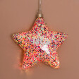 Personalised Hanging Pink Glitter LED Star Light lit up against beige coloured backdrop