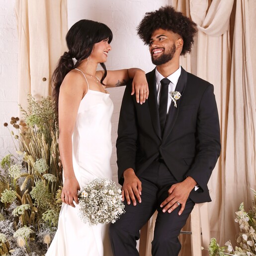 A model shot of a husband and wife looking at eachother lovingly, he wears the posy that matches her boquet