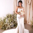 A full body picture of the model wearing a bodycon, wedding dress with the posy