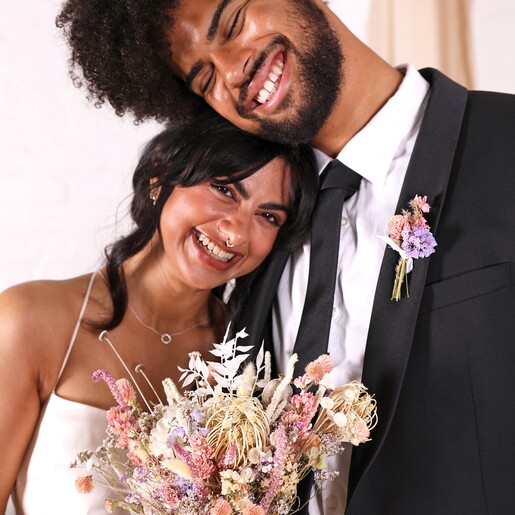 A husband and wife on their wedding day. The husband is wearing a buttonhole posy