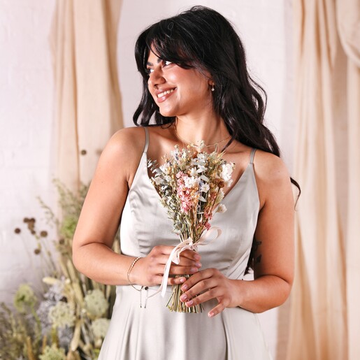 A model in a green bridesmaid dress holding a posy