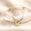 Blue Miyuki Bead Turtle Charm Cord Anklet in Gold with other version on top of neutral coloured material