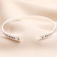 Close up of opening on Laugh a Little Harder Meaningful Word Bangle in Silver against beige material