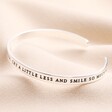Other side of quote on Laugh a Little Harder Meaningful Word Bangle in Silver against neutral fabric