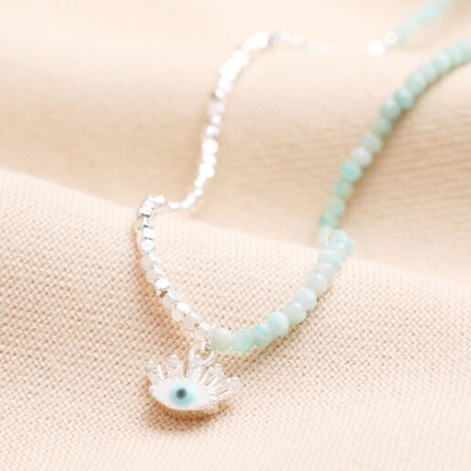 Blue Stone Beaded Evil Eye Pendant Necklace in Silver on beige fabric