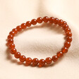 January red agate Birthstone Semi-Precious Stone Beaded Bracelet on top of neutral fabric