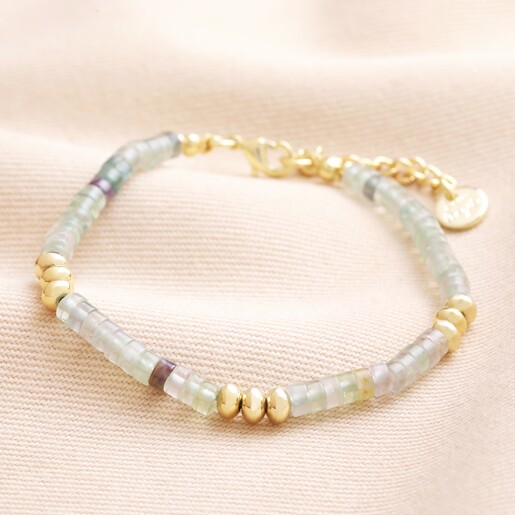 Green Semi-Precious Stone Heishi Beaded Bracelet in Gold on top of beige coloured fabric