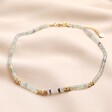 Green Semi-Precious Stone Heishi Beaded Necklace in Gold laid on top of beige coloured material