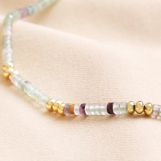 Close up of beads on Green Semi-Precious Stone Heishi Beaded Necklace in Gold against neutral coloured fabric