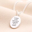 Back of Meaningful Word Enamel Flower Pendant Necklace in Silver showing quote against beige fabric