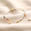 Multicoloured Miyuki Bead Cord Anklet in Gold on top of beige coloured fabric