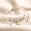 Blue Miyuki Bead Turtle Charm Cord Anklet in Gold on top of beige coloured fabric