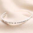 A New Chapter Meaningful Word Bangle in Silver on top of beige material