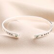 Close up of ends of A New Chapter Meaningful Word Bangle in Silver against neutral material