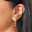Close up of Pearl and Crystal Star Charm Huggie Hoop Earrings in Silver on model