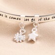 Close up of charms on You Are Loved Meaningful Word Bangle in Silver against beige backdrop
