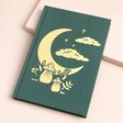 Gold Foil Celestial Toadstool Green Fabric Notebook on a Beige Background.