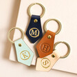 Personalised Initial Leather Diamond Keyrings in different shades on top of raised beige surface