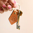 Model holding Personalised Initial Leather Diamond Keyring in tan colour against beige background