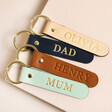 Personalised Name Leather Keyrings in blue, pink, tan and navy on top of raised beige surface