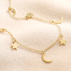 Gold Stainless Steel Star and Moon Charm Necklace arranged on top of beige coloured fabric
