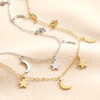 Gold Stainless Steel Star and Moon Charm Necklace next to silver version on top of neutral fabric