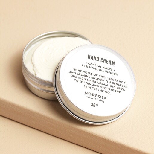 Norfolk Natural Living Coastal Walks Pocket Hand Cream open with cream inside against beige backdrop