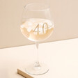 Personalised Gold Milestone Birthday Gin Glass on top of beige raised surface