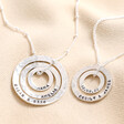 Personalised Sterling Silver Hammered Halo Necklaces next to each other on top of beige coloured fabric