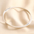 Personalised Hammered Sterling Silver Twisted Bangle against neutral coloured fabric