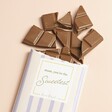 Sweetest Mum Milk Chocolate Bar with broken pieces of chocolate against beige backdrop