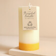 The Recycled Candle Company Ginger and Lime Pillar Candle with tag against beige coloured backdrop