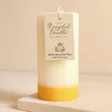 The Recycled Candle Company Ginger and Lime Pillar Candle with tag against beige coloured backdrop