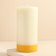 The Recycled Candle Company Ginger and Lime Pillar Candle on top of raised beige surface