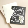 Rifle Paper Co. World's Greatest Dad Father's Day Card slotted inside of envelope against beige background