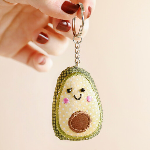 Model holding Sass & Belle Happy Avocado Keyring against beige backdrop
