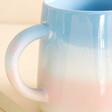Close up of handle on Sass & Belle Pastel Blue and Pink Ombre Mug against beige background