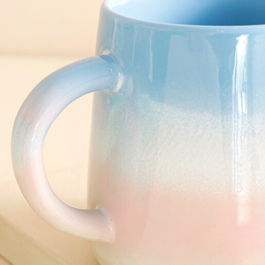 Close up of handle on Sass & Belle Pastel Blue and Pink Ombre Mug against beige background