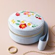 Personalised Embroidered Flowers Mini Round Velvet Jewellery Case closed with jewellery outside against beige backdrop