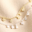Dainty Flower Charm Anklet in Silver next to gold version on beige material
