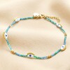 Evil Eye Blue and Green Seed Bead Anklet in Gold on top of beige coloured fabric