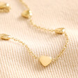 Close Up of Gold Stainless Steel Tiny Round Heart Charm Anklet on Beige Fabric