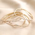 Set of 5 Clear Crystal Tennis Bracelets in Gold on top of beige coloured fabric
